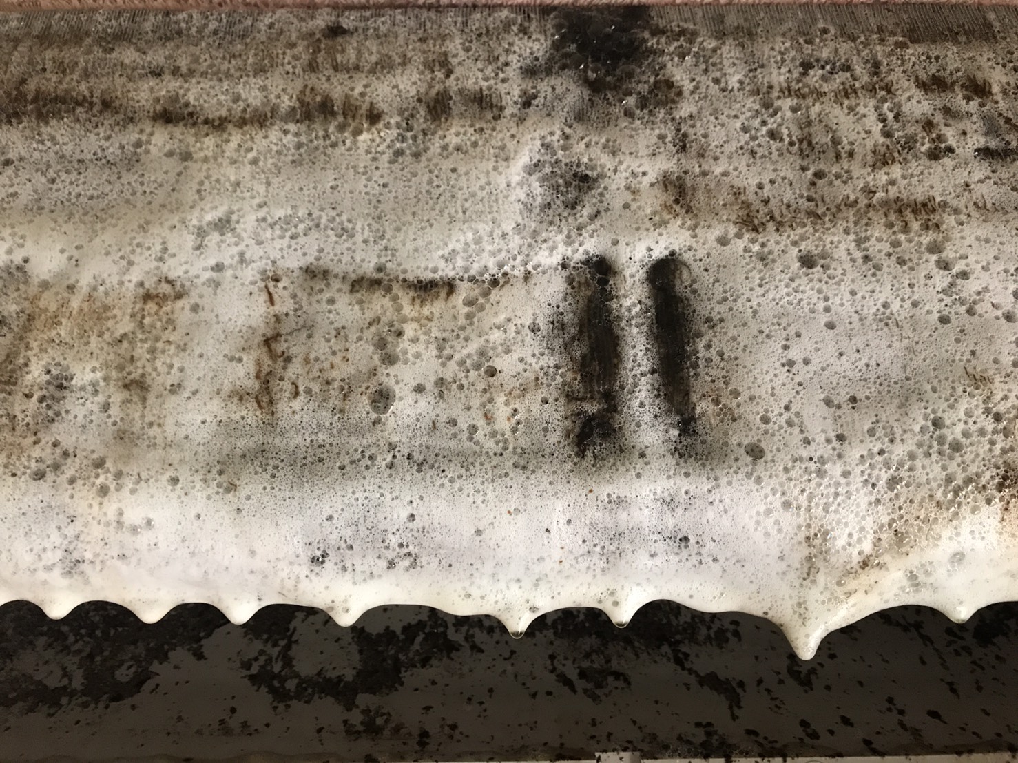 SK-105 重油污鋁潔劑清洗中：噴灑後附著層鬆動並產生大量泡沫，灰黑污水開始排出