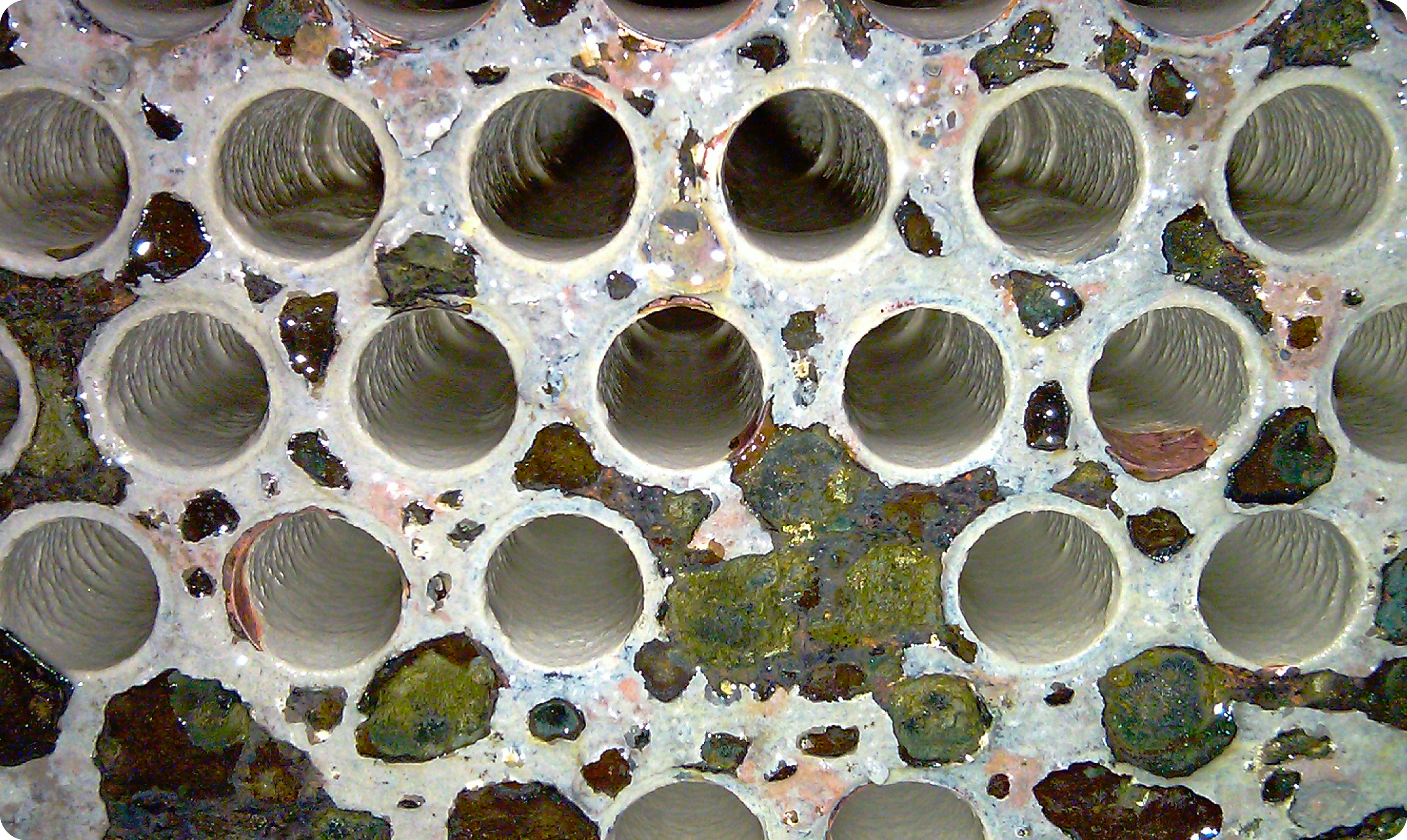 冷凝器管束特寫，矽酸鹽垢呈白硬且光滑，顯示酸洗不易滲透，難以直接反應的玻化現象